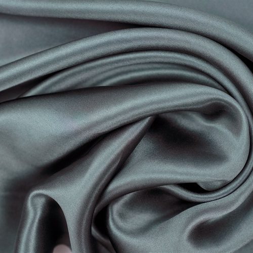 Luxurious dark gray 16 momme silk fabric with an elegant sheen, gracefully draped with soft folds and curves, showcasing its smooth, silky texture ideal for hair and skin care as a Pillowtex 100% Mulberry Silk Pillowcase | Zipper Enclosure, 16 Momme.